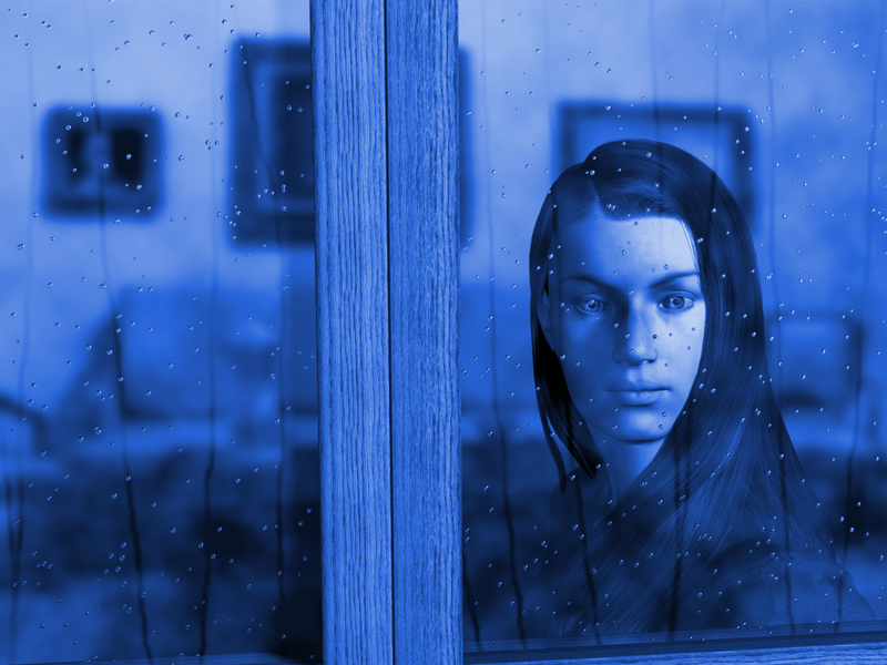 A woman looking through a window on a rainy day